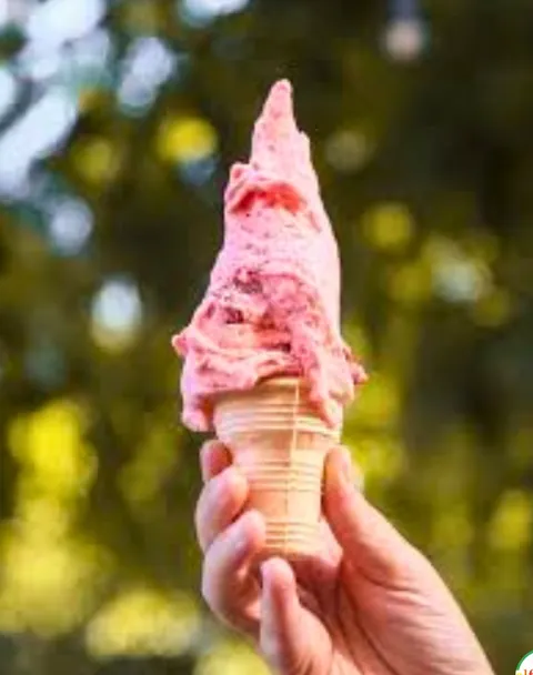 Cucurucho de helado rosado al sol, entre árboles