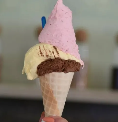 Cucurucho de tres bochas (frutilla, crema y chocolate) recién servido en Alfredito